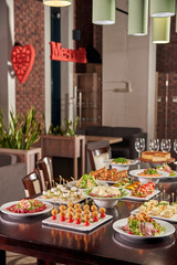 The table is full of delicious snacks, sandwiches, salad and other delicacies. Translation of the word-decor in the background: dream. A festive table in a cafe, restaurant.