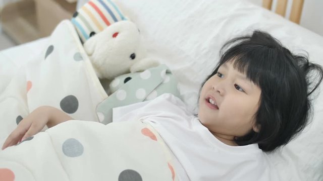 Slow motion 4K close up of young Asian mother smiling & waking up her daughter in morning