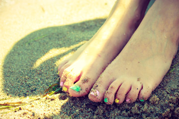 Woman feet with nail polish on sand