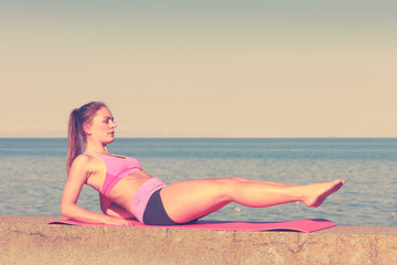 Fototapeta premium Woman doing sports exercises outdoors by seaside