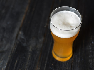 Light unfiltered wheat beer in a glass on a black table with copy space