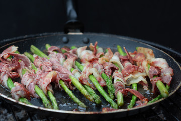Bacon wrapped asparagus in frying pan.