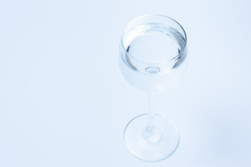 Mineral water in a wine glass close up from under angle close up on white background.