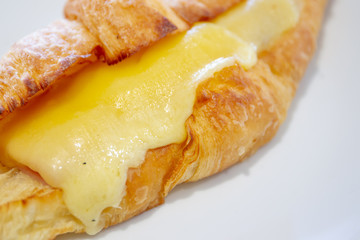 Baked ham - cheese croissant in a dish on wooden table close up.