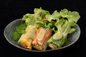 Fresh vegetable noodle spring roll with sauce on plate, Salad roll, On a black background. Diet or cook concept.
