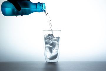 Man filling some water into a double glass with a cobe of ices on white background.
