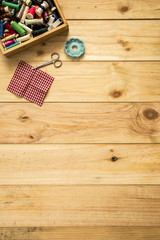 Box of tailor, scissors and sewing threads with colorful bobbins for patchwork on wooden background with space for text