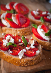 Close-up of bruschetta with cheese, tomatoes, fresh basil and balsamic vinegar on cutting board