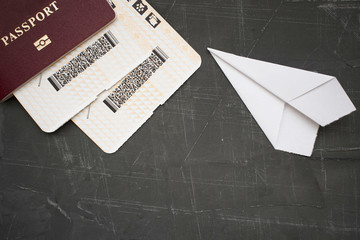 passport, tickets and paper airplane on a concrete background, top view