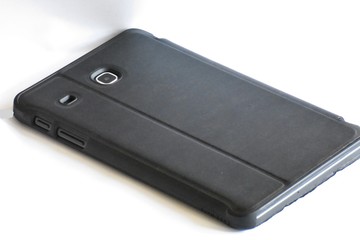 tablet isolated, in a black case, with camera lens on white background