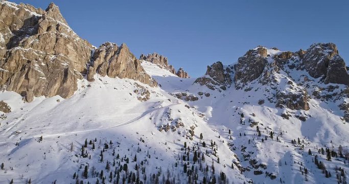 Forward aerial to snowy rocky mountain at falzarego pass.Sunset or sunrise, clear sky, sunny.Winter Dolomites Italian Alps mountains outdoor nature establisher.4k drone flight