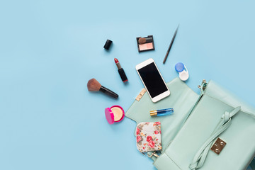 Topview of Fashionable female accessories watch glasses lipstick perfume and blue bag. Overhead of essentials for any girl, on blue background
