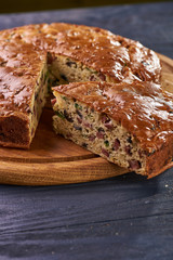 A piece of unusual unsweetened pie in the foreground. Corn wheat pie with various options of salty stuffing in the background. Snack cake with sausage, olives, vegetables, greens, meat.