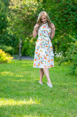 Beautiful young girl in a dress walking in the summer Park