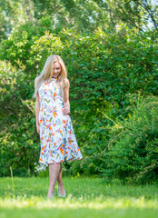 Beautiful young girl in a dress walking in the summer Park