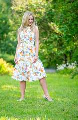 Beautiful young girl in a dress walking in the summer Park