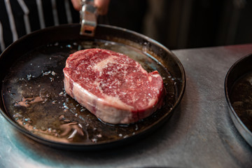 Raw meat Ribeye steak with a large salt on cast iron frying pan