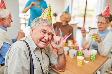 Alter Mann mit Partyhut feiert Geburtstag - obrazy, fototapety, plakaty