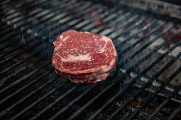 A perfect 1 inch thick New York strip loin steak, seasoned and grilling over the flame on the barbecue