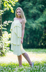 Beautiful young girl in a dress walking in the summer Park