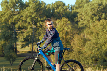 Fototapeta na wymiar A cyclist rides the hills, Beautiful portrait of a guy on a blue bicycle