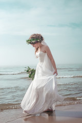 Fototapeta na wymiar Bride on the beach with wedding bouqet soft copy space