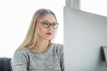 Eine junge Frau sitzt auf der Arbeit am Computer und liest etwas