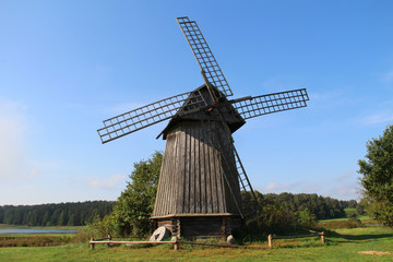 Fototapeta na wymiar Old wooden windmill on a green field in nature