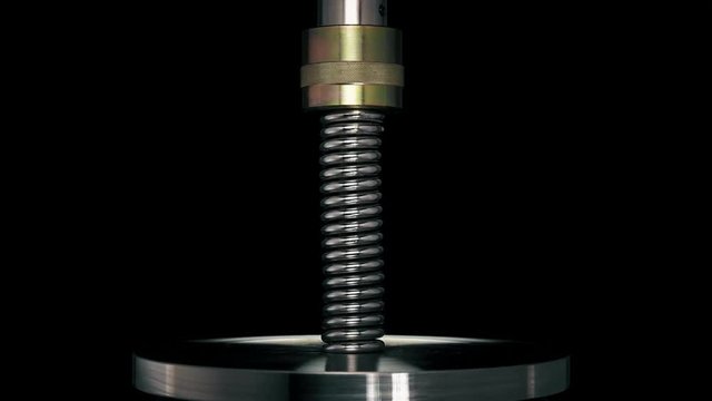 test of reliability of a spring, compression and decompression by a hydraulic press, close-up