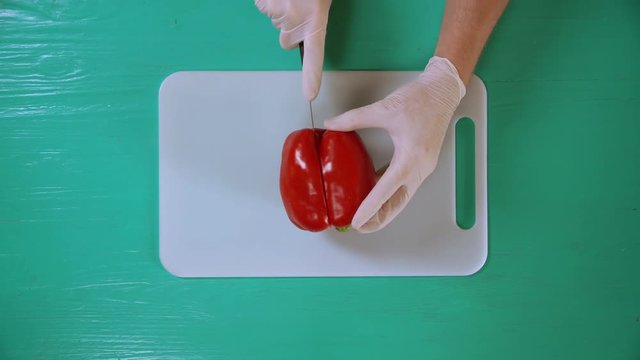 man using knife and cutting board to chop fruit. he removes core and the seeds from plant.