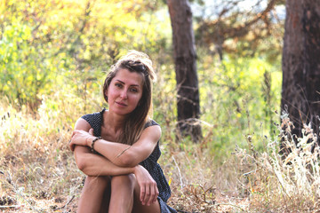 beautiful girl sits in autumn forest, sunny day.