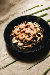 Delicious meal with shrimps in black plate, traditional Aisan food