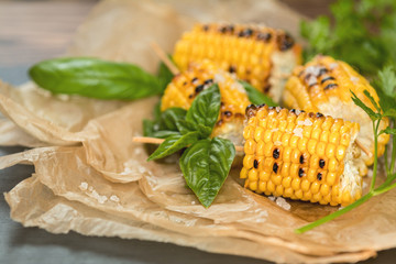 Corn baked in olive oil, with pepper, salt and basil on blue dish on a black stone surface