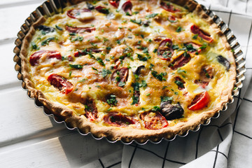 Male hand cutting delicious pizza with cheese, tomatoes and herbs, traditional Italian cuisine