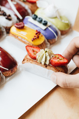 Male hand taking delicious sweets with glaze, colorful dessert