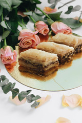 Baklava sweet dessert and pink roses. Pastry made of layers of filo filled with chopped nuts and sweetened and held together with syrup or hone