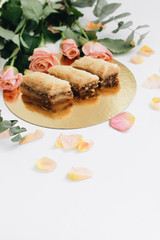 Baklava sweet dessert and pink roses. Pastry made of layers of filo filled with chopped nuts and sweetened and held together with syrup or hone
