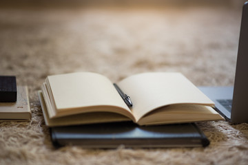 A neat arrangement of notebooks, laptop, folder and hard drive, placed in a horizontal row towards a warm light filtering in from above. The promise of productivity