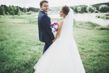 Newly married couple running and jumping in park while holding hands