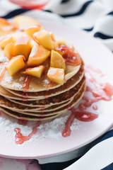 Stack of delicious homemade pancakes with sauce and sliced apple