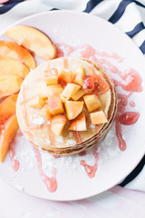 Stack of delicious homemade pancakes with sauce and sliced apple