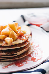 Stack of delicious homemade pancakes with sauce and sliced apple