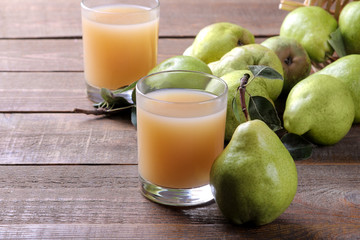 Pear juice in a glass with fresh ripe pears on a brown wooden table