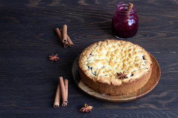 Homemade tasty shortcrust pie with fruit or jam, crumble and spices (cinnamon, anise) on old wooden table background. 
