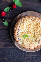 Homemade shortcrust fruit or jam pie with crumble and fresh berries with mint on old wooden table background. Homemade pastry with fruit or berry (cherry, plum, strawberry, raspberry) jam.