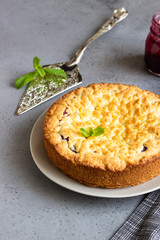Homemade tasty shortcrust pie with fruit or jam, crumble and mint on grey concrete background.