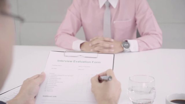Slow motion - Attractive young Asian businessman in a job interview with corporate personnel manager who reading his CV. Asia businessman talking to male candidate at desk, interviewing job applicant.