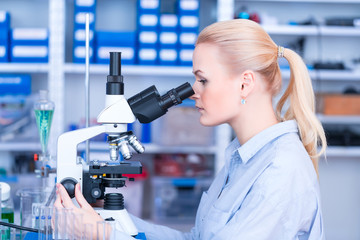 Girl with a slide for the microscope University Hospital. Attractive young scientist  looking at the microscope slide in the forensic laboratory