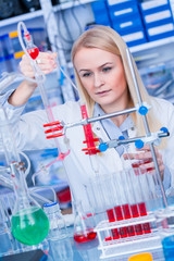 Female laboratory assistant with chemical experiment in scientific laboratory. Female medical or scientific researcher using test tube on laboratory.