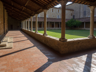 Innenhof eines Klosters mit Säulen und grünem Rasen im Abendlicht, Siena, Toskana, Italien